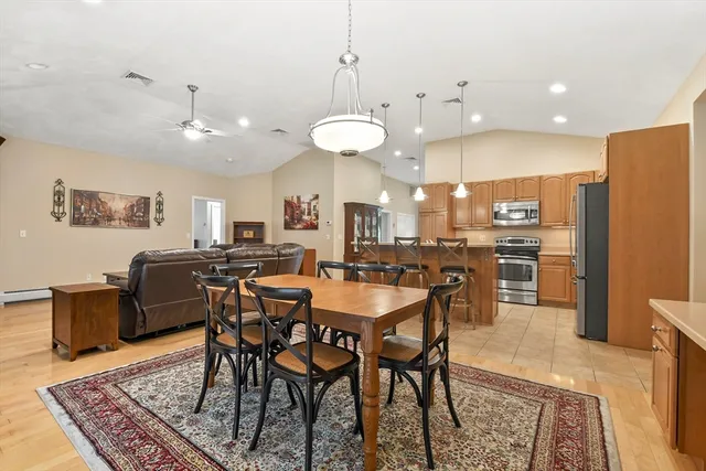 a kitchen with stainless steel appliances granite countertop a stove a sink a microwave a dining table and chairs with wooden floor