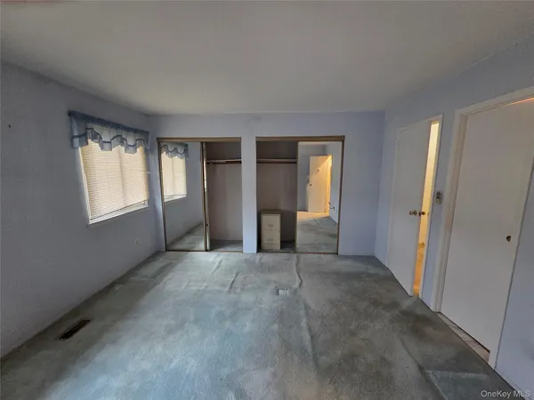 an empty room with windows and closet