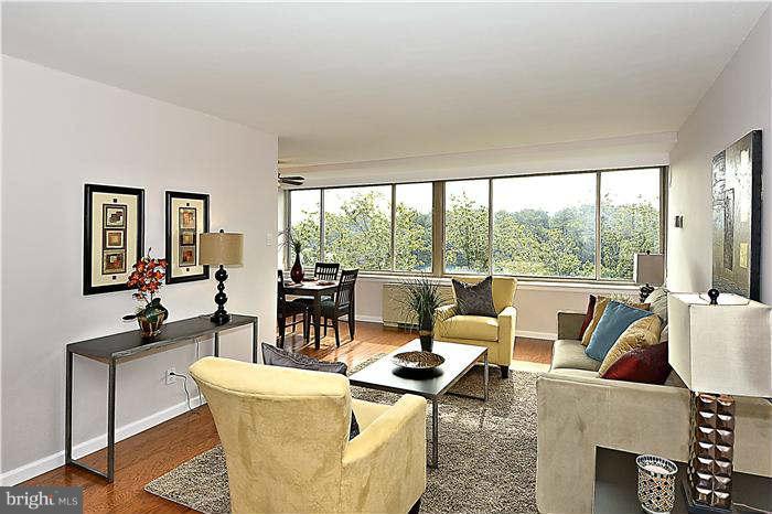 a living room with couches and a large mirror next to a window