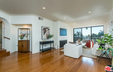 a living room with furniture a potted plant and a large window