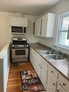 a kitchen with granite countertop a sink a stove and microwave