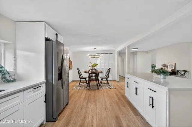 a kitchen with stainless steel appliances kitchen island granite countertop a refrigerator a stove top oven a sink dishwasher and white cabinets with wooden floor