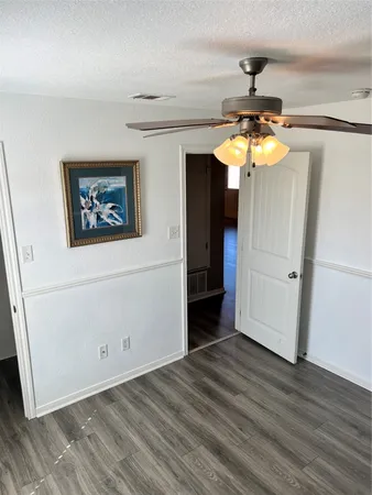 a view of a hallway with wooden floor and chandelier