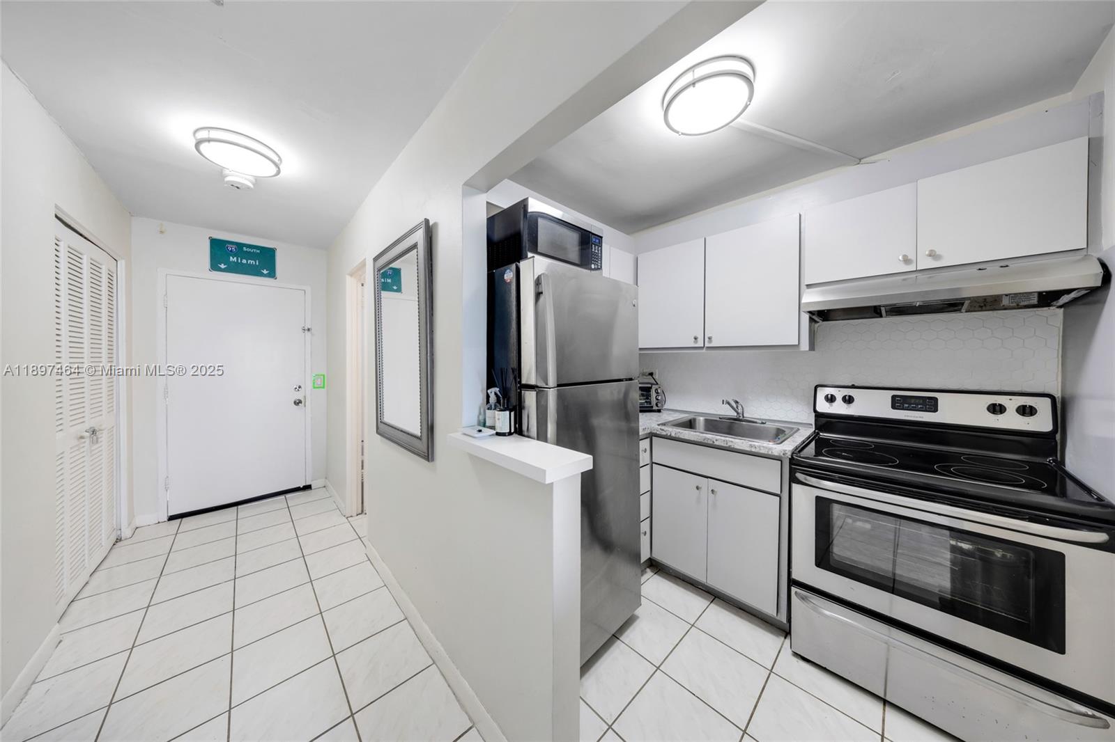 7904 West Drive, Unit 1010 North Bay Village, FL 33141 - Photo 16 of 25 a kitchen with white cabinets and stainless steel appliances