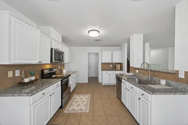 a kitchen with granite countertop a sink and white cabinets