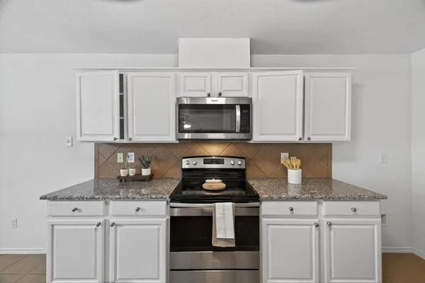 a kitchen with granite countertop white cabinets and black appliances