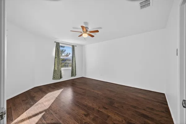 an empty room with wooden floor fan and windows