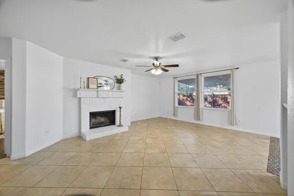 a view of a livingroom with a fireplace a ceiling fan and windows