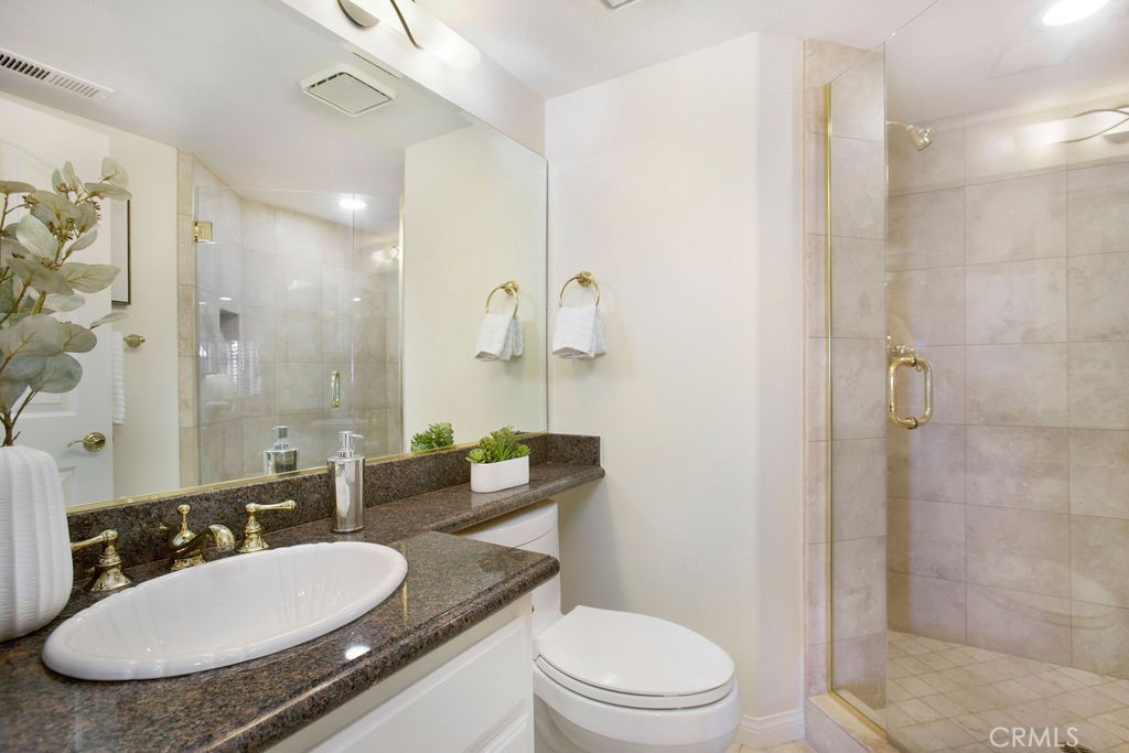 22 Callender Court Laguna Niguel, CA 92677 - Photo 25 of 67 a bathroom with a granite countertop sink a toilet a mirror and shower