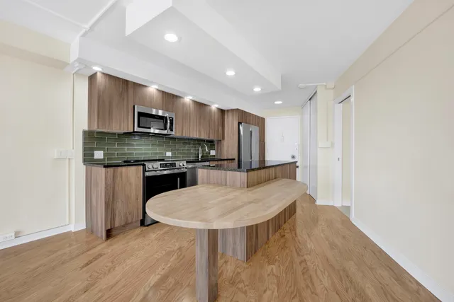 a kitchen with kitchen island a stove a table and a refrigerator