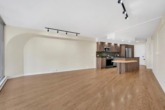 a view of kitchen with stainless steel appliances wooden floor and a refrigerator