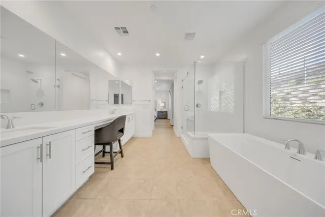 a bathroom with a bathtub a sink a window and a mirror