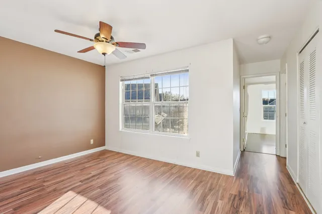 a view of empty room with wooden floor and fan