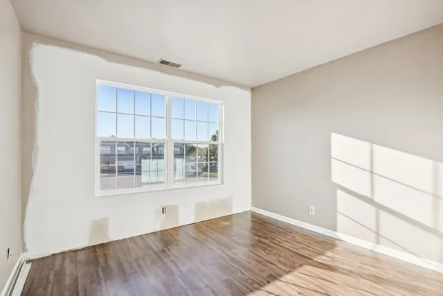 a view of an empty room with wooden floor and a window