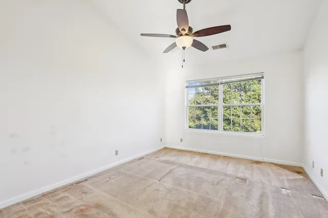 an empty room with a window and a fan
