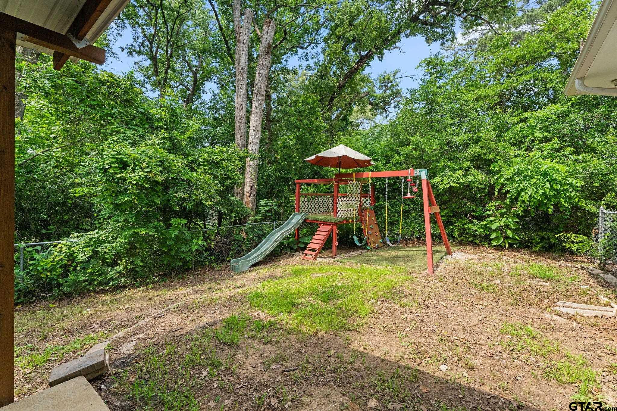 2811 Rollingwood Drive Tyler, TX 75701 - Photo 23 of 28 a view of a backyard with a small cabin and slide