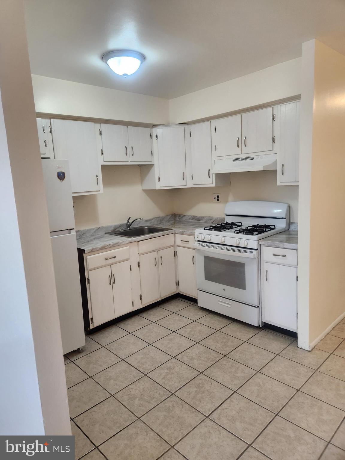 4320 Howell Street, Unit 1 Philadelphia, PA 19135 - Photo 8 of 19 a kitchen with stainless steel appliances granite countertop a sink a stove a refrigerator and white cabinets