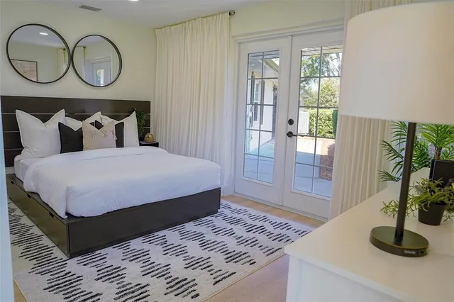 a bedroom with a bed a mirror and windows