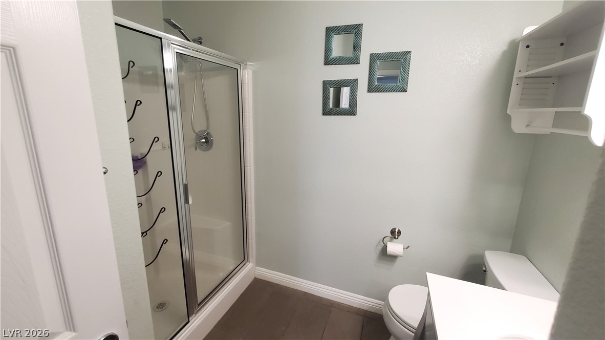 7903 Dell Ridge Avenue Las Vegas, NV 89179 - Photo 6 of 20 A well-appointed bath features a shower with sliding glass doors and convenient wall-mounted shelving.