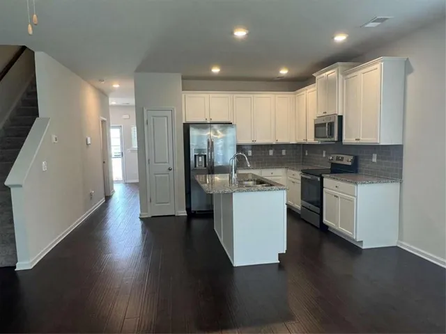 a kitchen with stainless steel appliances granite countertop a refrigerator a sink a stove a microwave and wooden cabinets