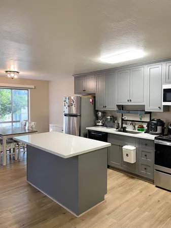 a kitchen with stainless steel appliances kitchen island granite countertop a table chairs sink refrigerator and cabinets