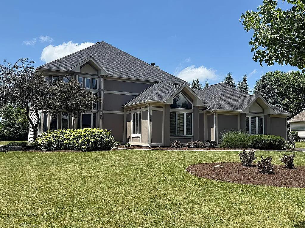 a front view of a house with a garden and trees