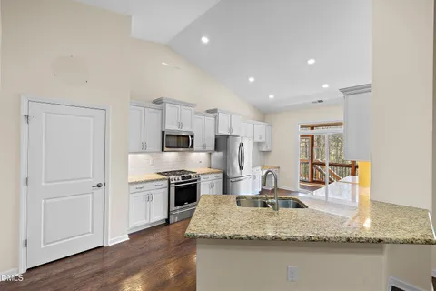 a large kitchen with granite countertop a large counter top stainless steel appliances and wooden floor