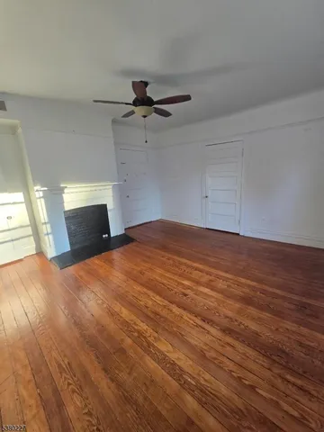 an empty room with wooden floor cabinet and windows
