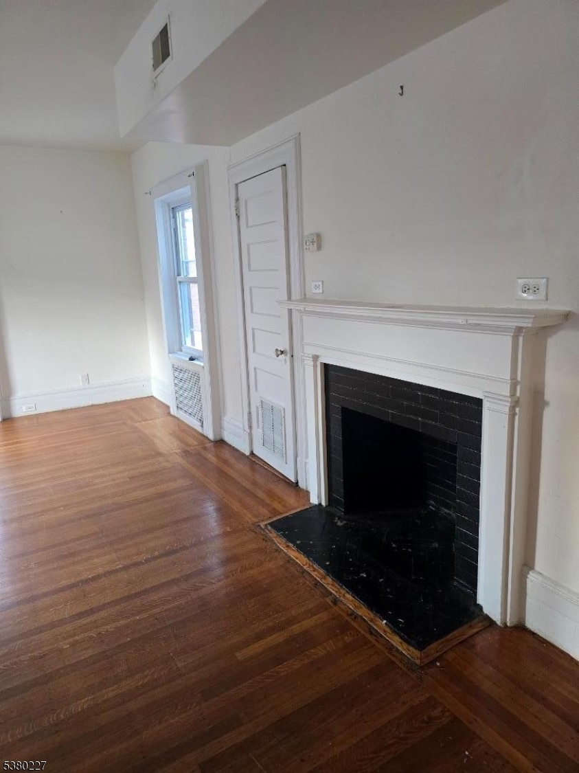 379-387 Mt Prospect Avenue, Unit 4 Newark, NJ 07104 - Photo 3 of 21 a view of an empty room with wooden floor fireplace and a window