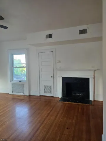 an empty room with wooden floor fireplace and windows