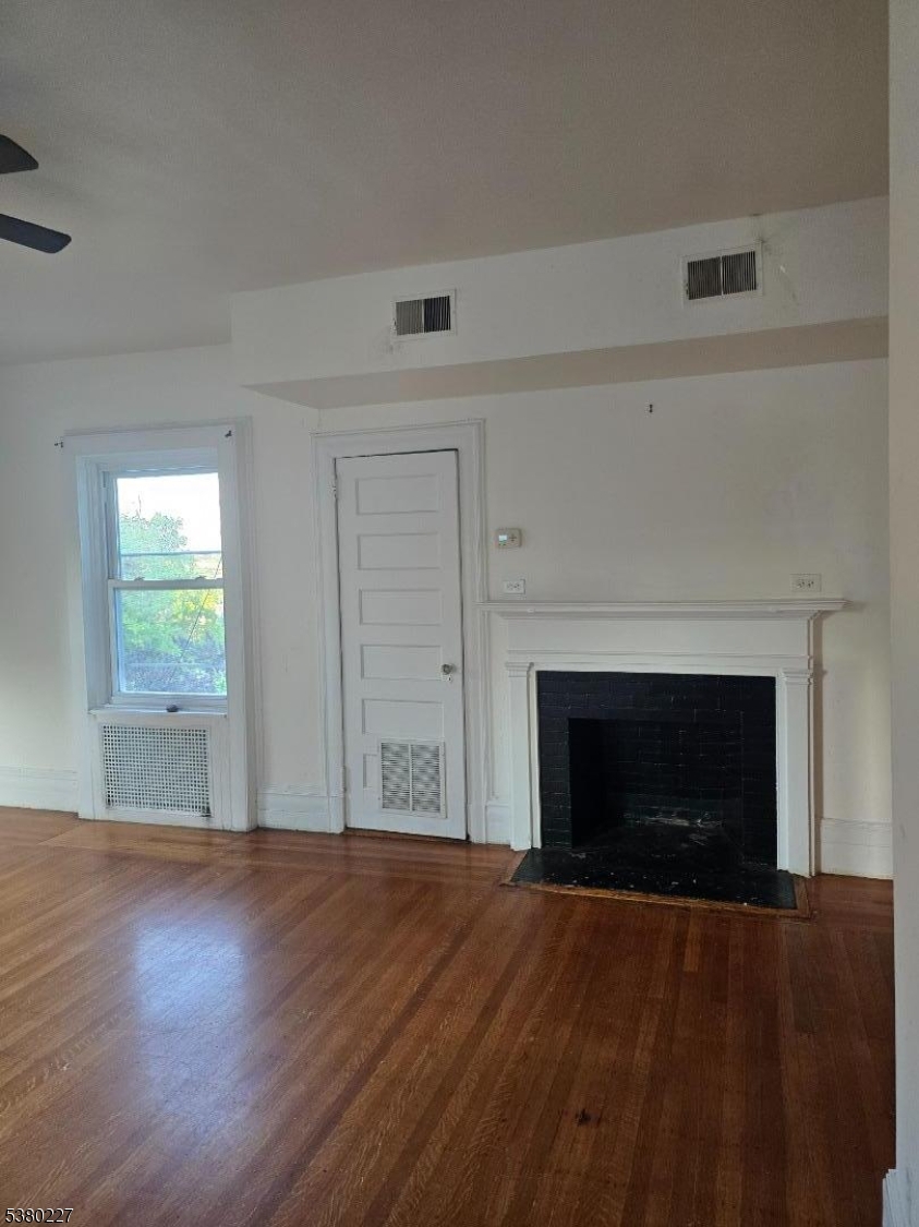 379-387 Mt Prospect Avenue, Unit 4 Newark, NJ 07104 - Photo 4 of 21 an empty room with wooden floor fireplace and windows
