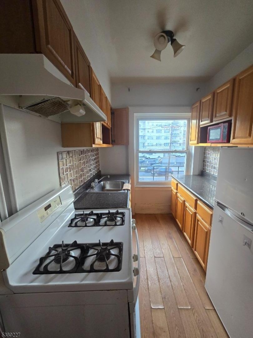379-387 Mt Prospect Avenue, Unit 4 Newark, NJ 07104 - Photo 7 of 21 a kitchen with wooden floors and a stove