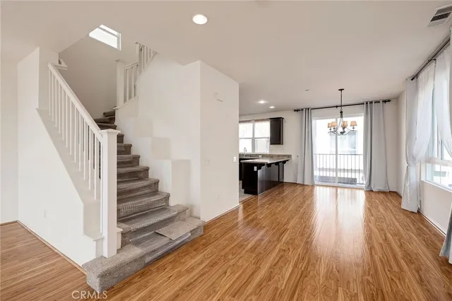 a view of an empty room with wooden floor and a kitchen