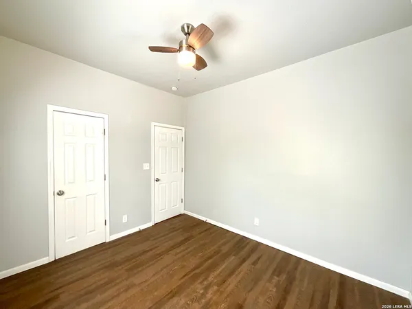 an empty room with wooden floor and fan