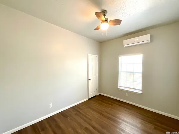 an empty room with wooden floor chandelier fan and windows