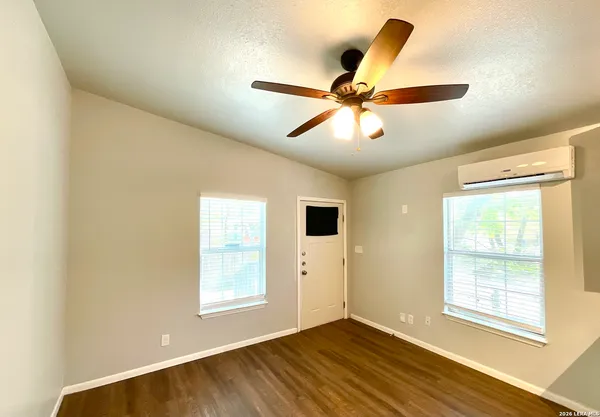 a view of an empty room with wooden floor and a window