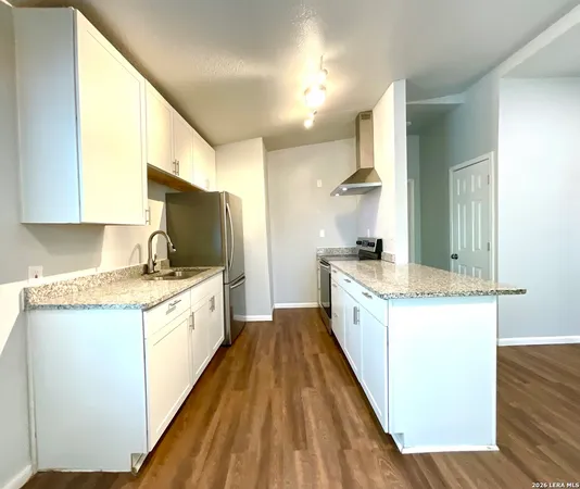 a large kitchen with granite countertop a large counter top space a sink stainless steel appliances and cabinets