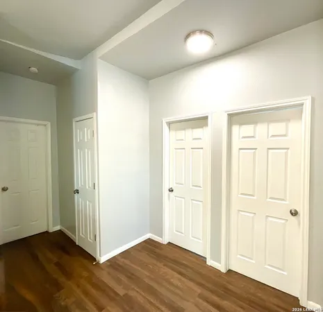 an empty room with wooden floor & windows