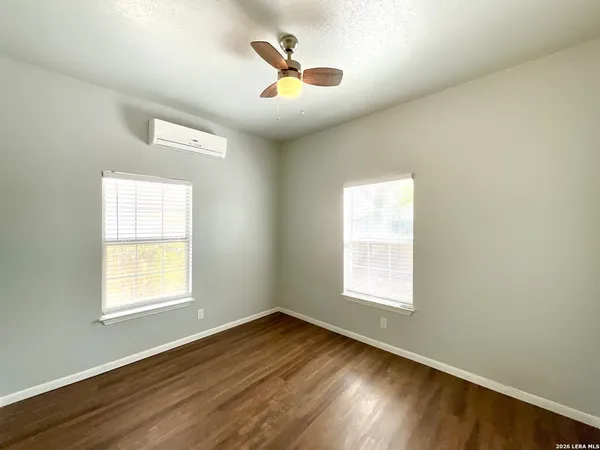 a view of an empty room with wooden floor and a window