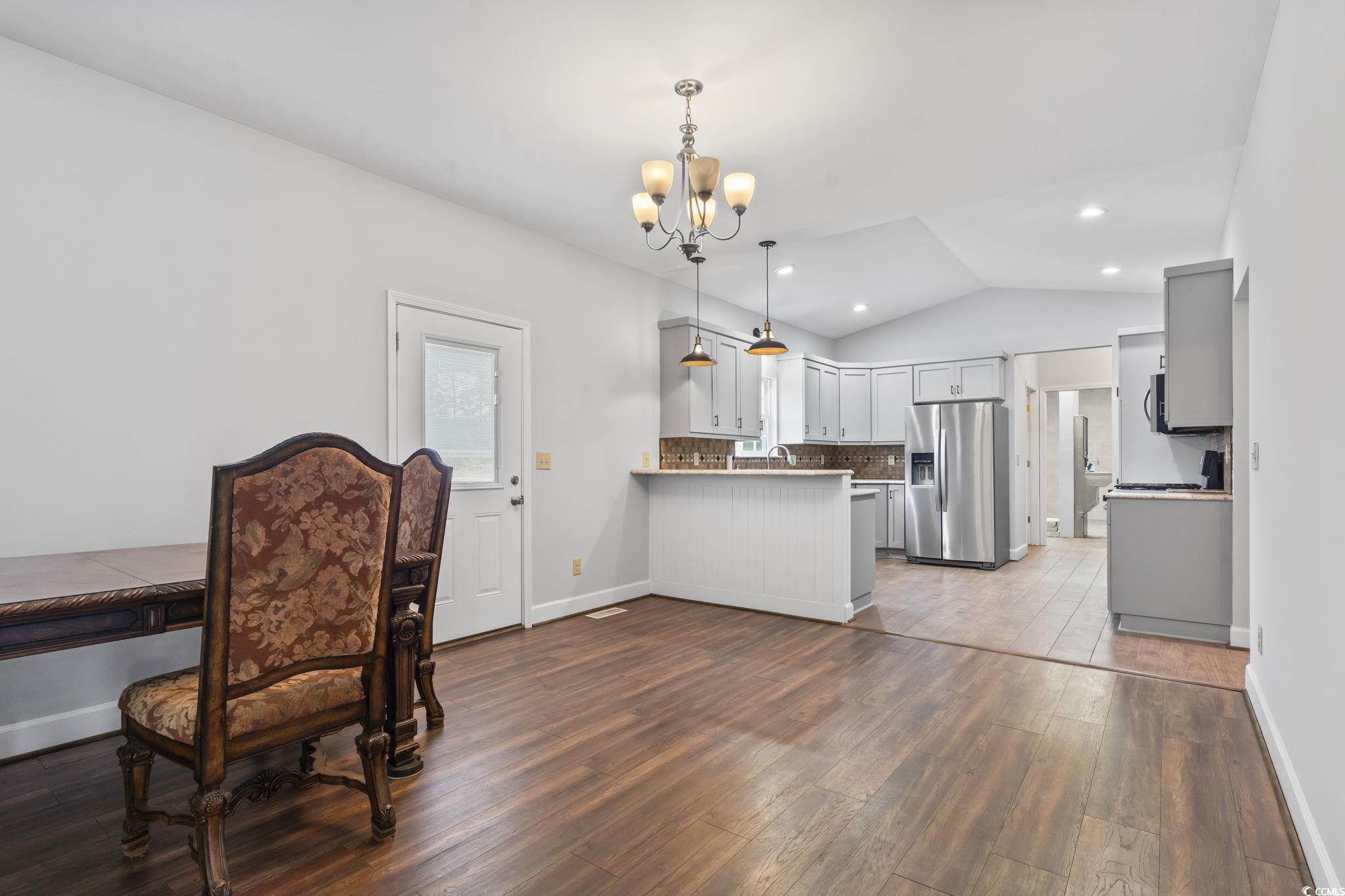 1585 Daisy Road Loris, SC 29569 - Photo 14 of 48 Kitchen with vaulted ceiling, a chandelier, stainless steel fridge with ice dispenser, dark wood-type flooring, and decorative light fixtures