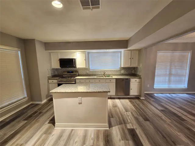 a kitchen with a sink window and stainless steel appliances