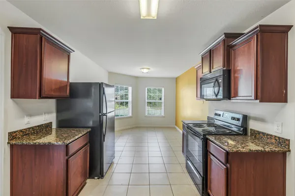 a kitchen with granite countertop a refrigerator and a stove top oven