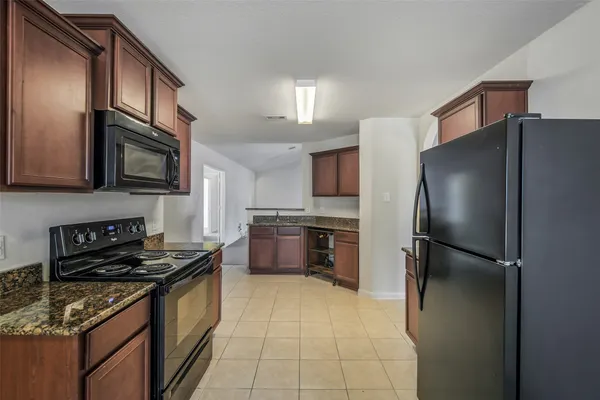 a kitchen with granite countertop a stove top oven microwave and cabinets