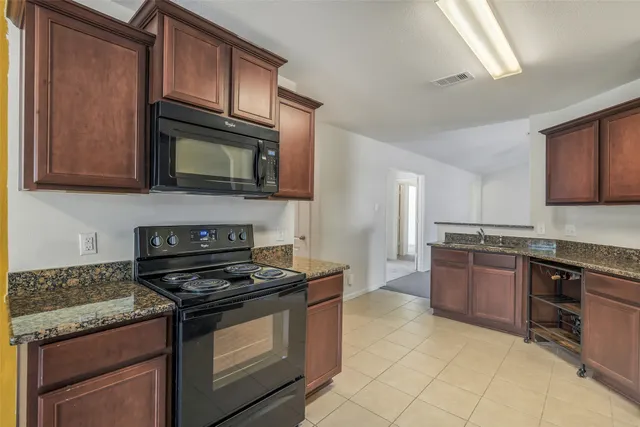 a kitchen with stainless steel appliances granite countertop a refrigerator sink and stove