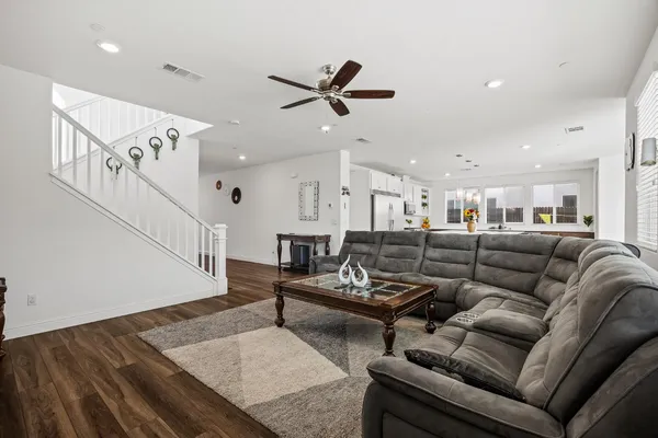a living room with furniture kitchen view and a wooden floor