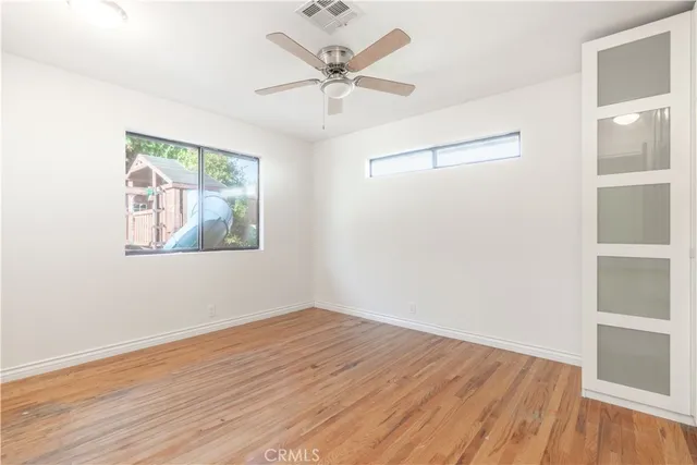 an empty room with wooden floor closet and windows