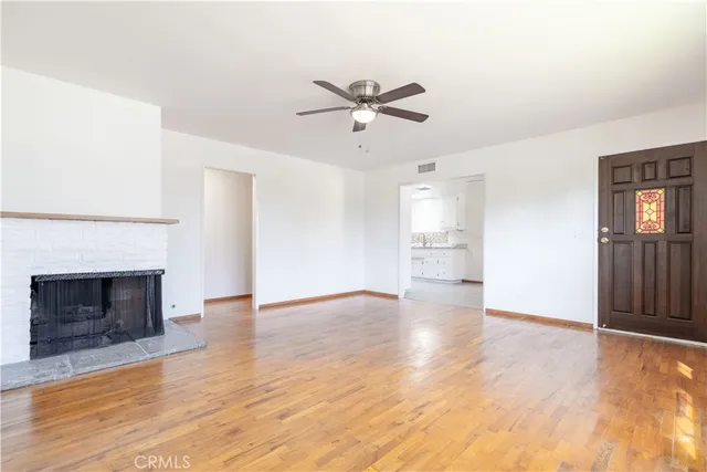 a view of an empty room with window and wooden floor