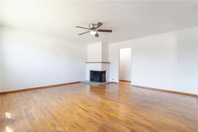 a view of empty room with wooden floor and fireplace