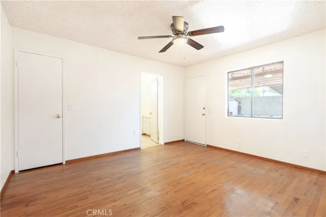 an empty room with wooden floor fan and windows