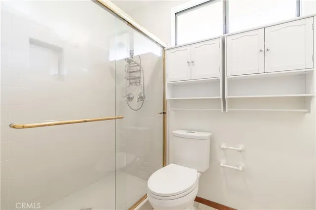 a white toilet sitting next to a shower